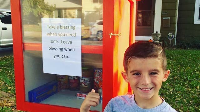 Six-year-old Paxton Burns stands in front of the food pantry he set up with the help of his mother Maggie Ballard