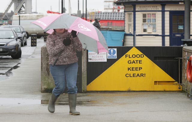 A woman walks past a flood gate on Harwich quay, Essex.