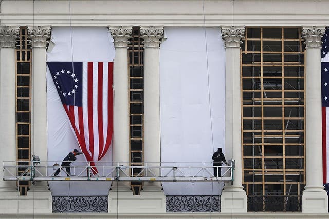 Workers hang an early version of the American flag on the U.S. Capitol to be used as part of the backdrop to the presidential inauguration for President elect Donald Trump as he prepares to take the reins of power next week