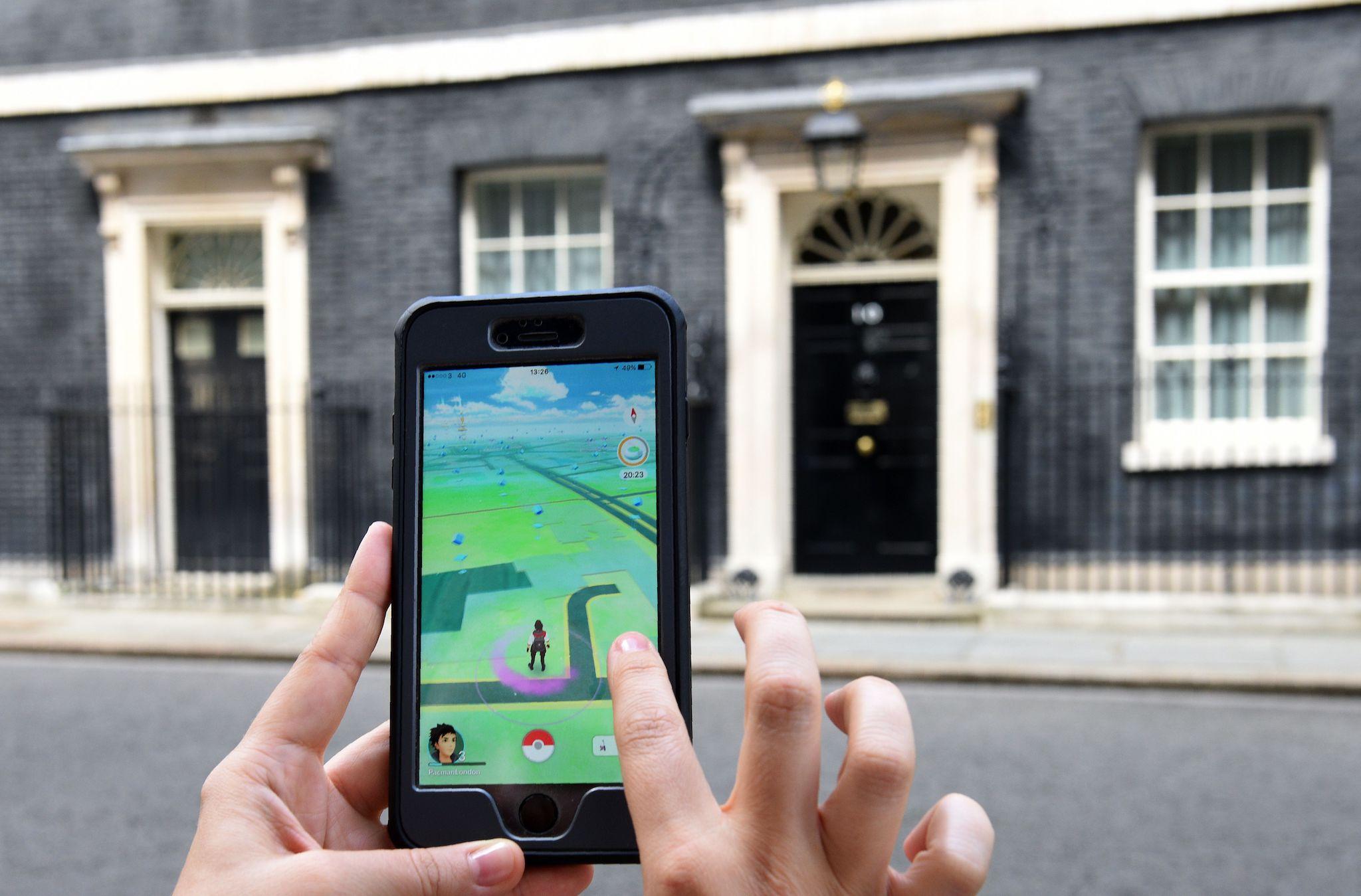 A picture taken on July 14, 2016 shows an avatar on the screen of a mobile phone as a player uses the Pokemon Go application on their mobile phone as they wait with members of the media opposite the door of 10 Downing Street in central London, as cabinet appointments by new prime minister Theresa May are made on her first full day in office