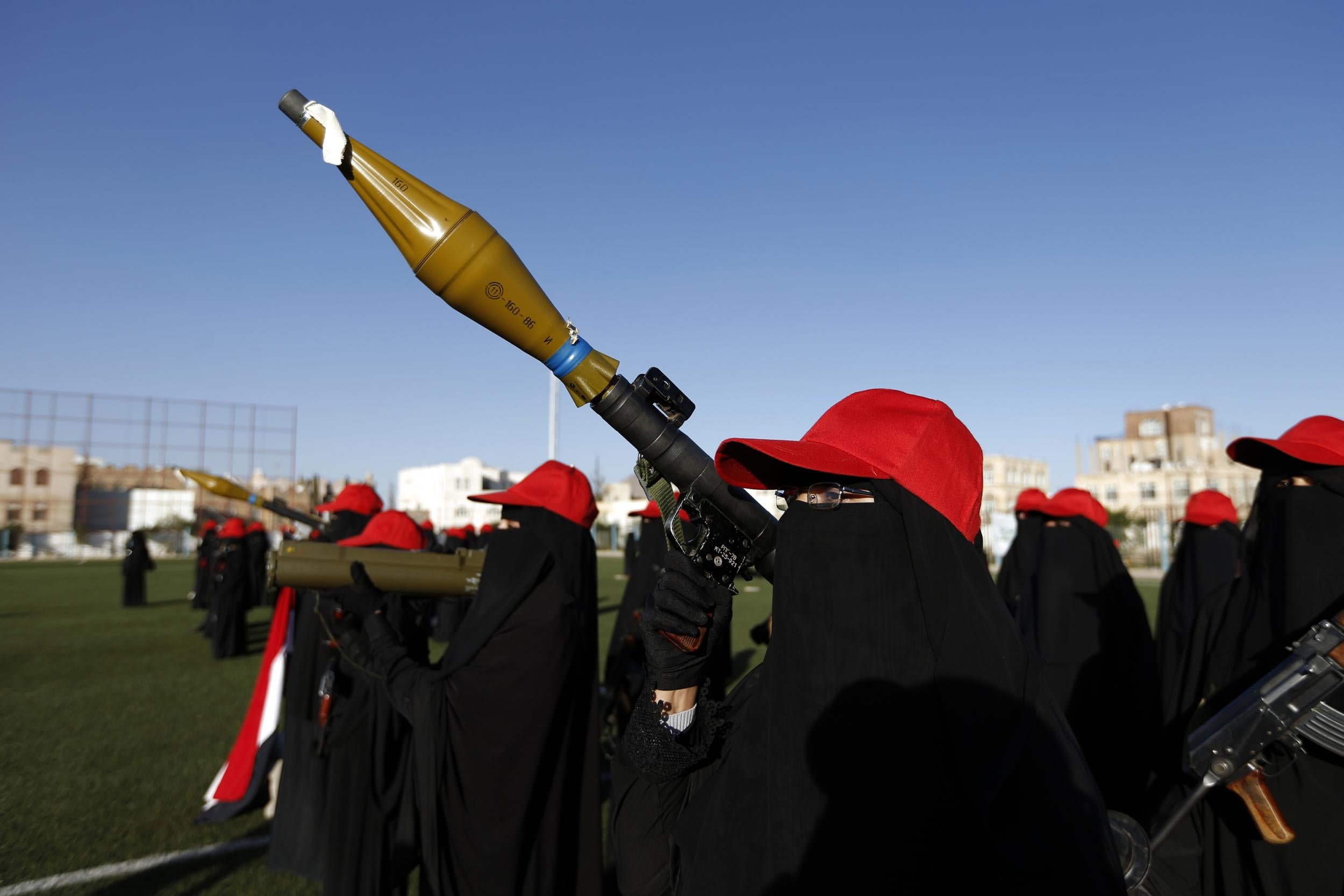 Women hold rocket launchers and sport red caps in support of the Huthi rebel movement