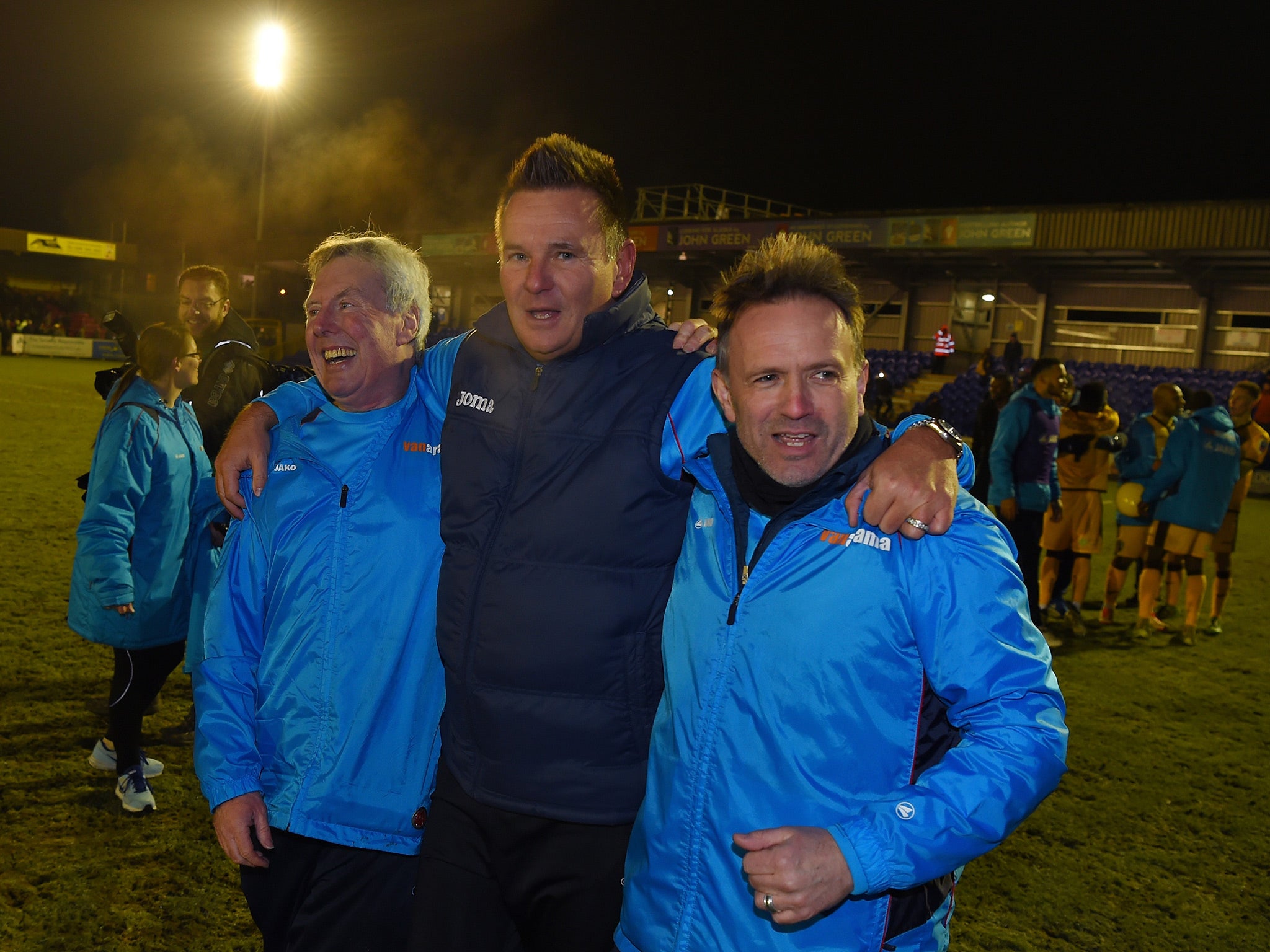 Paul Doswell, Sutton's manager, celebrates his side's victory on the pitch at Kingsmeadow