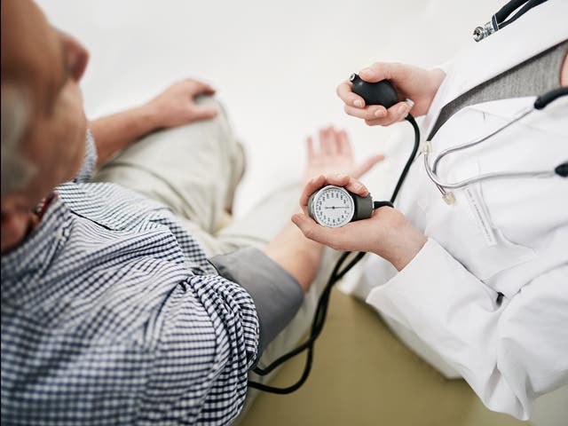 A doctor checks a senior patient's blood pressure in her office 