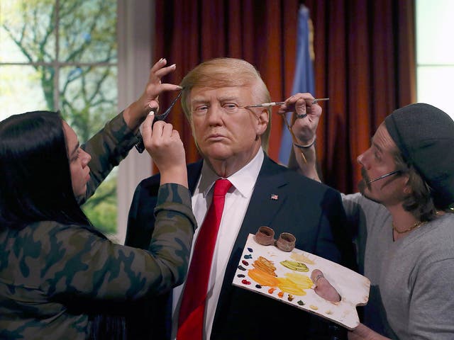 Gallery assistants pose, pretending to put the finishing touches to the hair and make-up of a waxwork of US President-elect Donald Trump, during a media event at Madame Tussauds in London