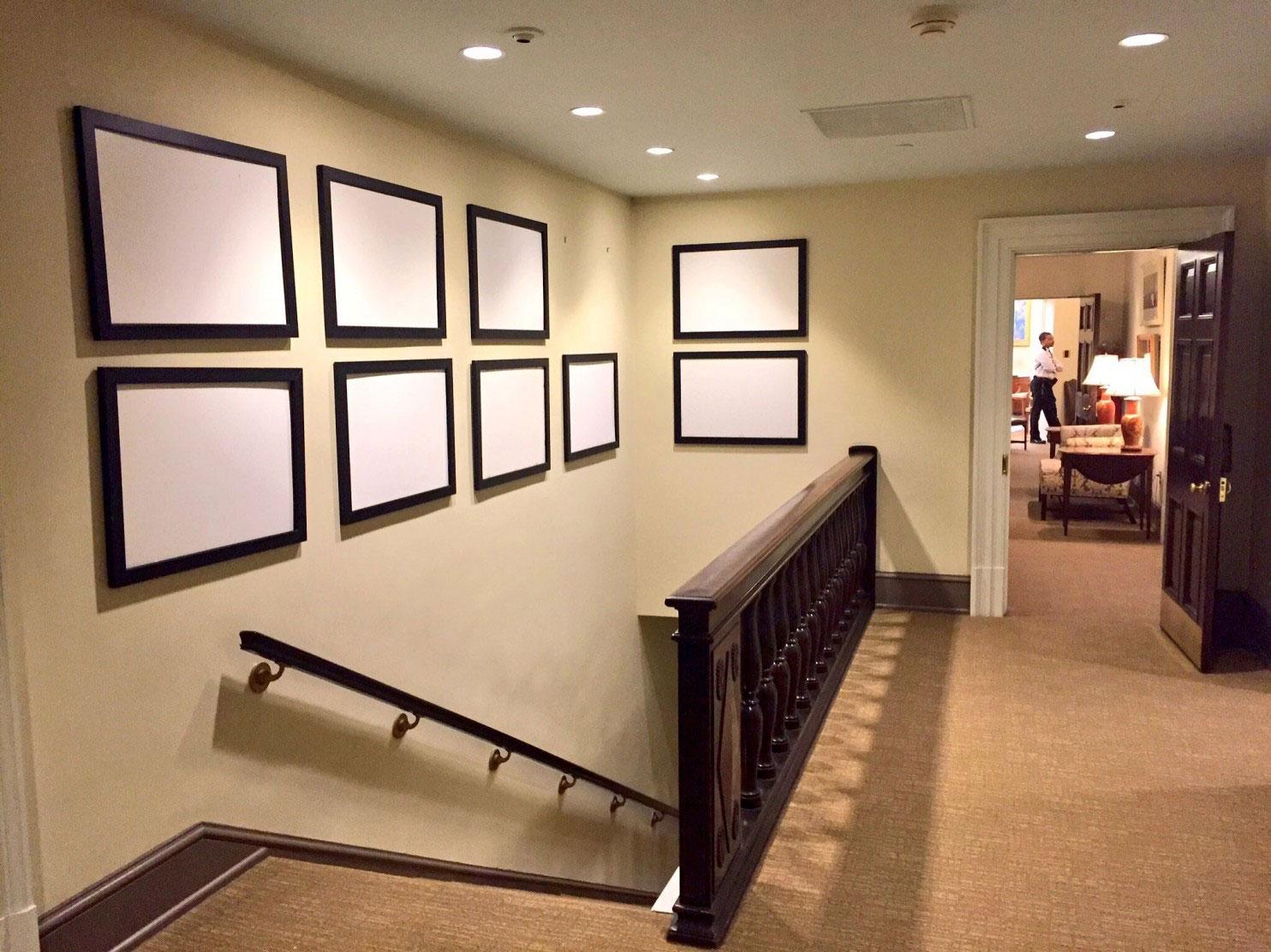 Empty frames that once contained photos of President Obama line the walls of the West Wing. The Oval Office can been seen down the hallway