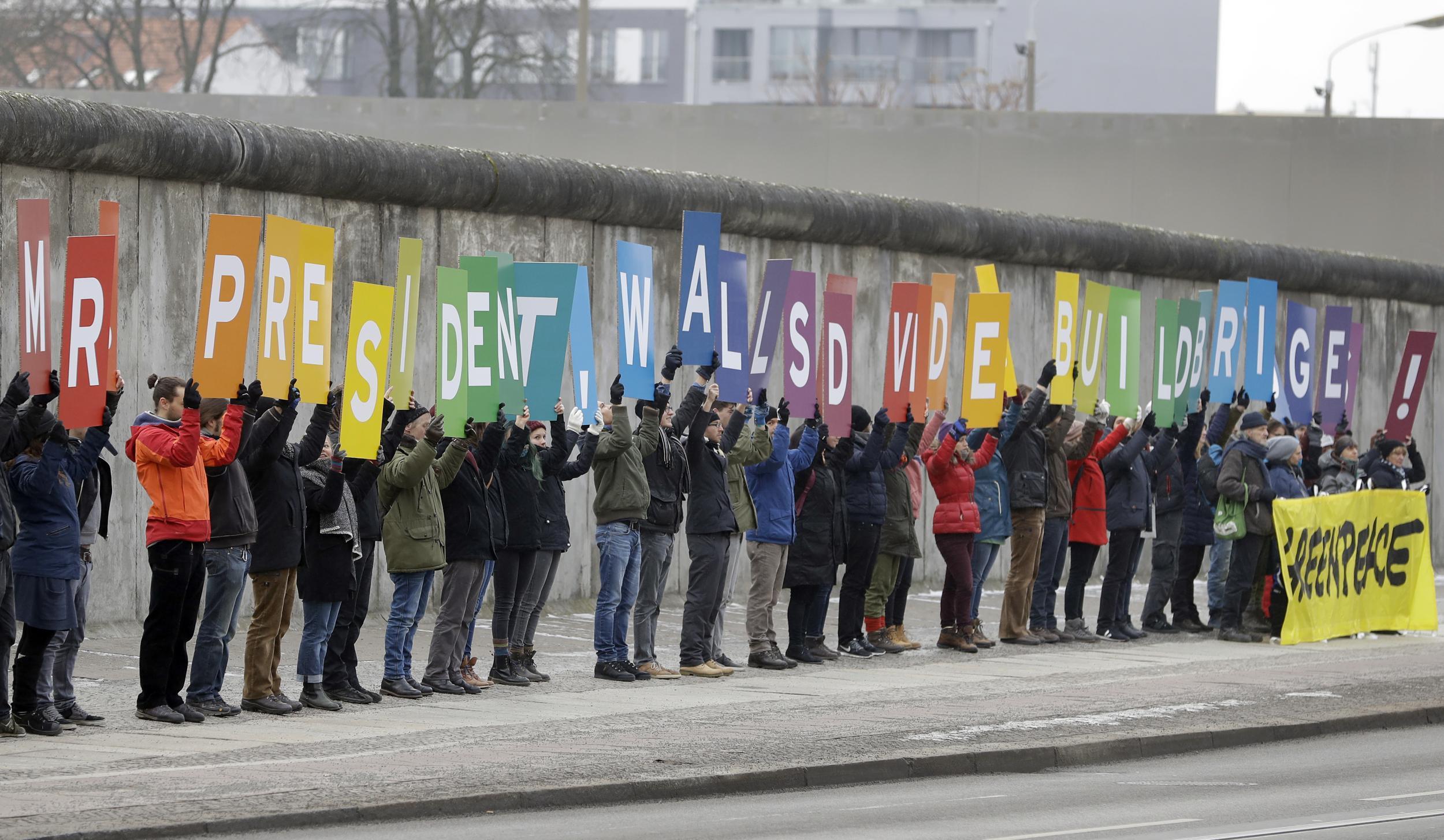 Activists from Greenpeace display a message reading "Mr President, walls divide. Build Bridges!" along the Berlin wall in Berlin on January 20, 2017 to coincide with the inauguration of Donald Trump as the 45th president of the United State