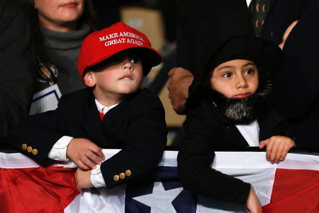 Children dressed up as Donald trump and former US President Abraham Lincoln wait to hear US Republican Presidential nominee Donald Trump address supporters at Macomb Community College