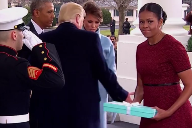 Ms Obama looks around for somewhere to put the ribbon-wrapped box, before shooting a swift look of desperation at the camera