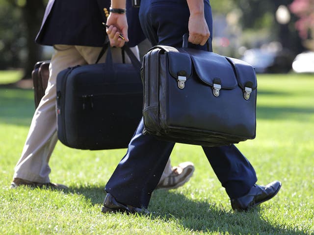 <p>A military aide to former President Obama carries the ‘football’, a case with the launch codes for nuclear weapons</p>