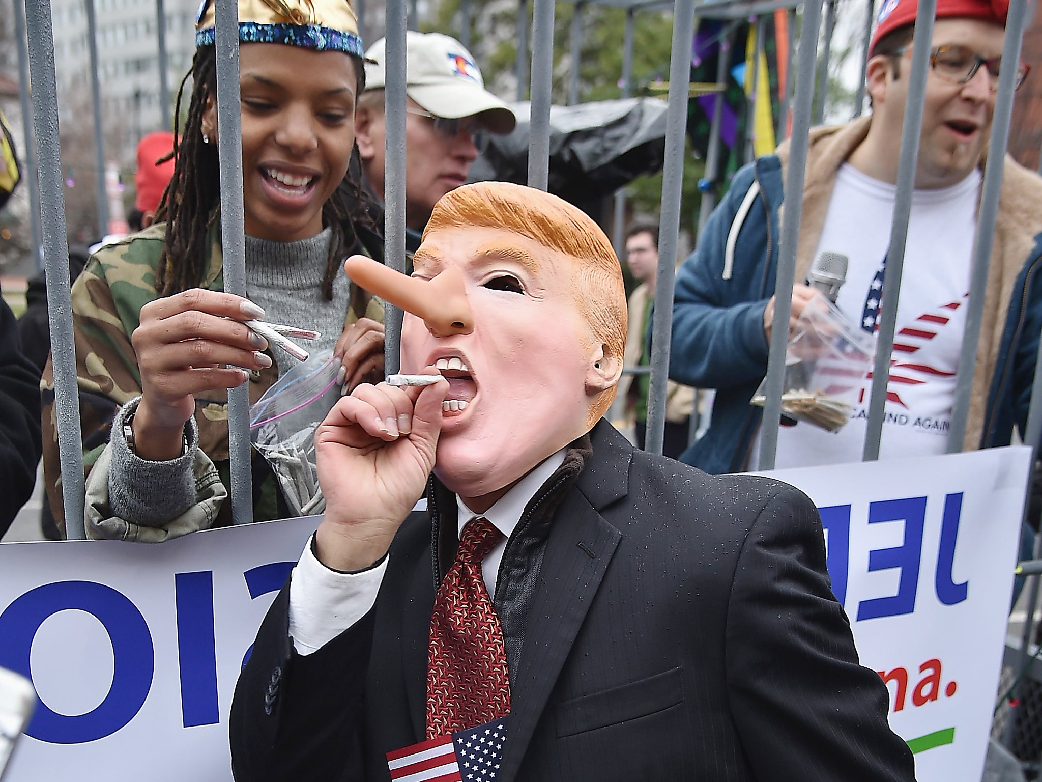 A protester with a spliff and a Donald Trump-Pinocchio mask attends a marijuana rally ahead of the President's inauguration