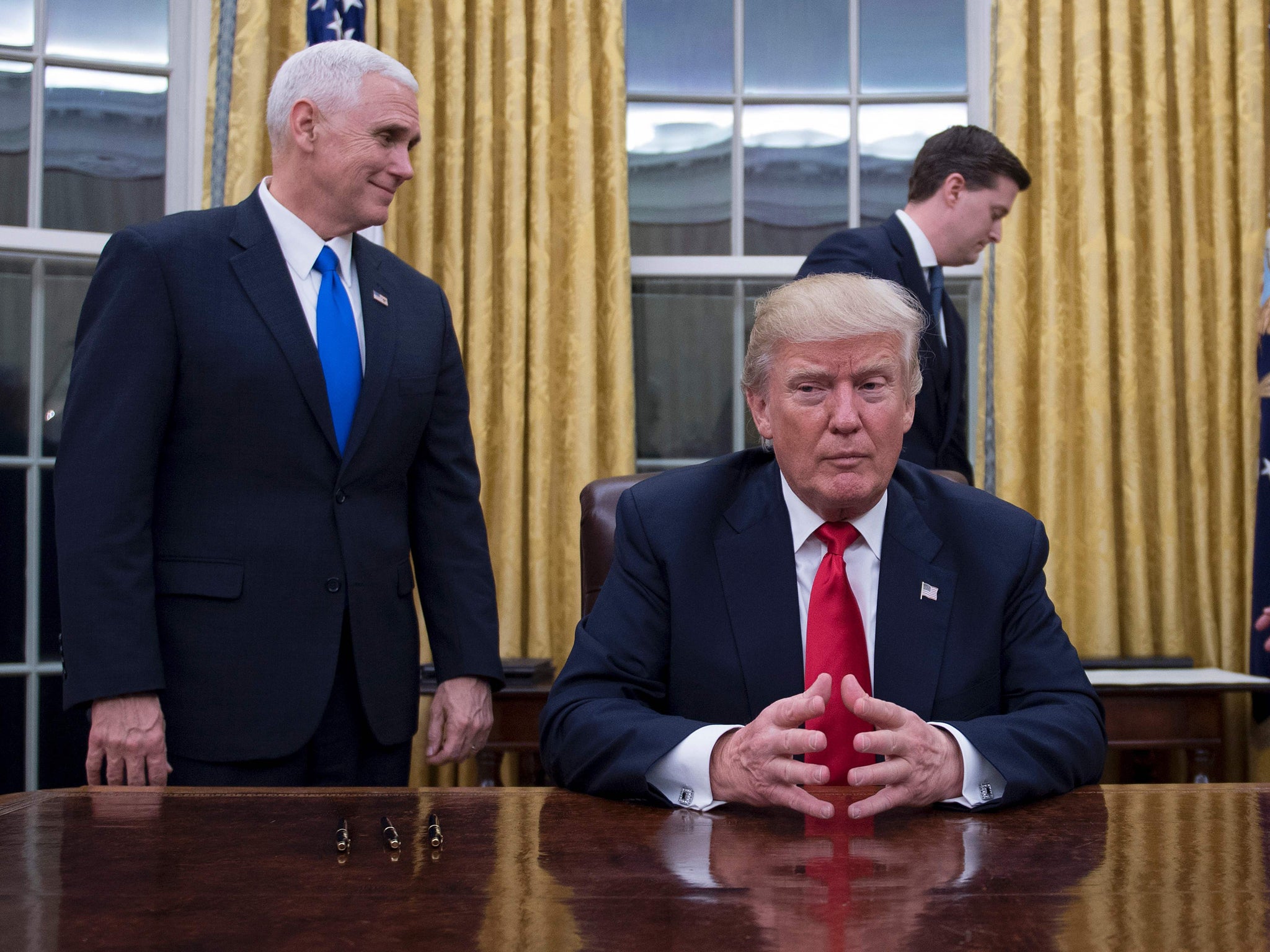 Donald Trump sits in the Oval Office for the first time, flanked by his Vice President Mike Pence and White House Chief of Staff Reince Priebus