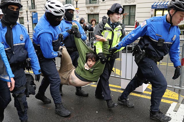 A protester is dragged away from a public access point to the National Mall on 14th Street NW prior to the inauguration in Washington DC