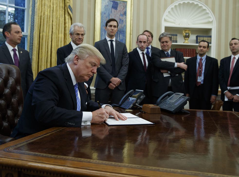 President Donald Trump signs an executive order implementing a federal government hiring freeze, Monday, Jan. 23, 2017, in the Oval Office of the White House in Washington