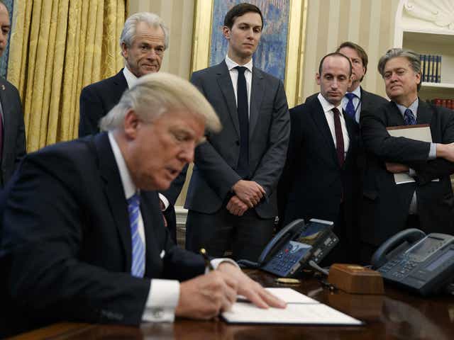 Mr Trump surrounded by men as he signs an executive order