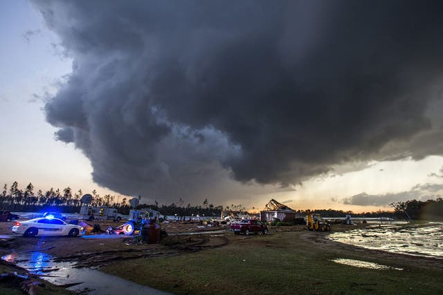 Storm clouds approach emergency crews at the scene of a house cut in half by a tornado near where seven people were killed outside Adel, Georgia USA on 22 January 2017