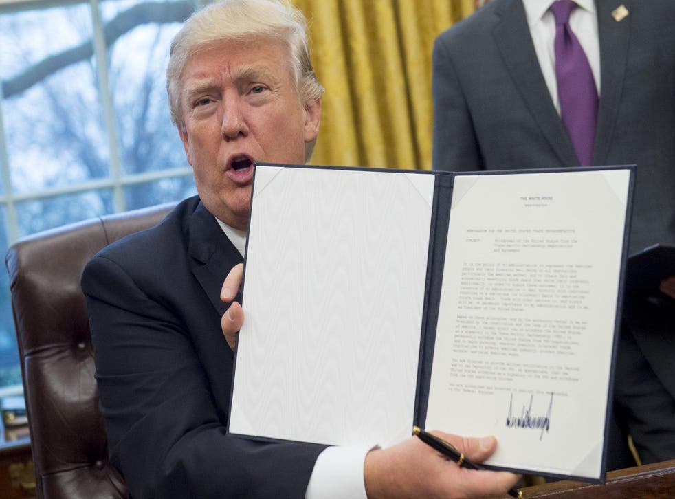 Donald Trump holds up an executive order withdrawing the US from the Trans-Pacific Partnership after signing it in the Oval Office of the White House in Washington, DC, January 23, 2017.