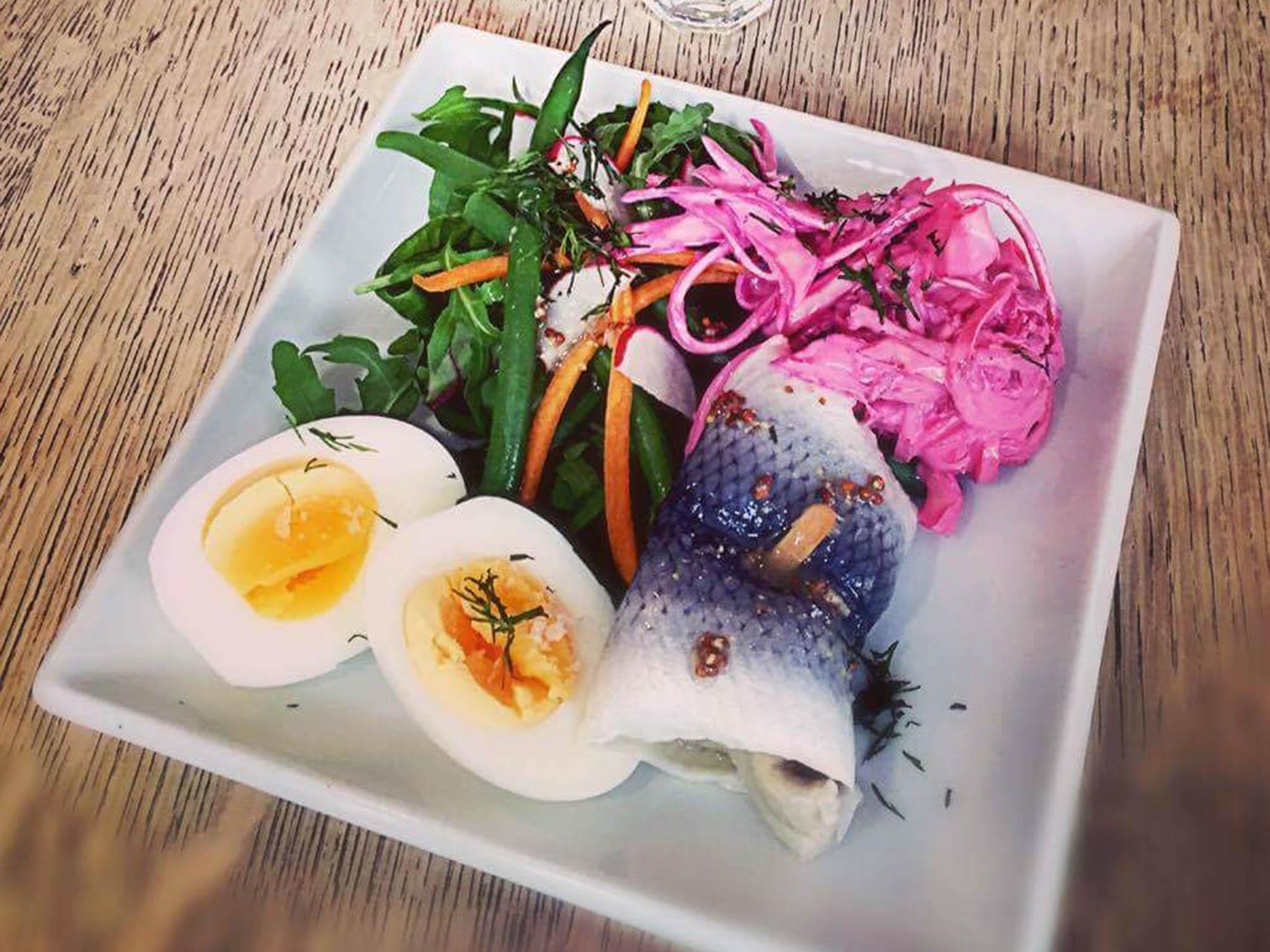 Small plates of mustard pickled herring is served with a beetroot slaw