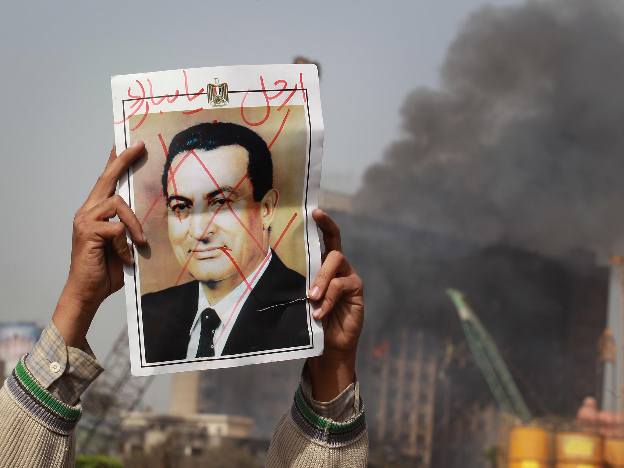 A protestor in Cairo’s Tahrir Square holds a photo showing President Mubarak’s face crossed out on 29 January, 2011