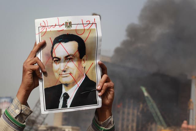 A protestor in Cairo’s Tahrir Square holds a photo showing President Mubarak’s face crossed out on 29 January, 2011
