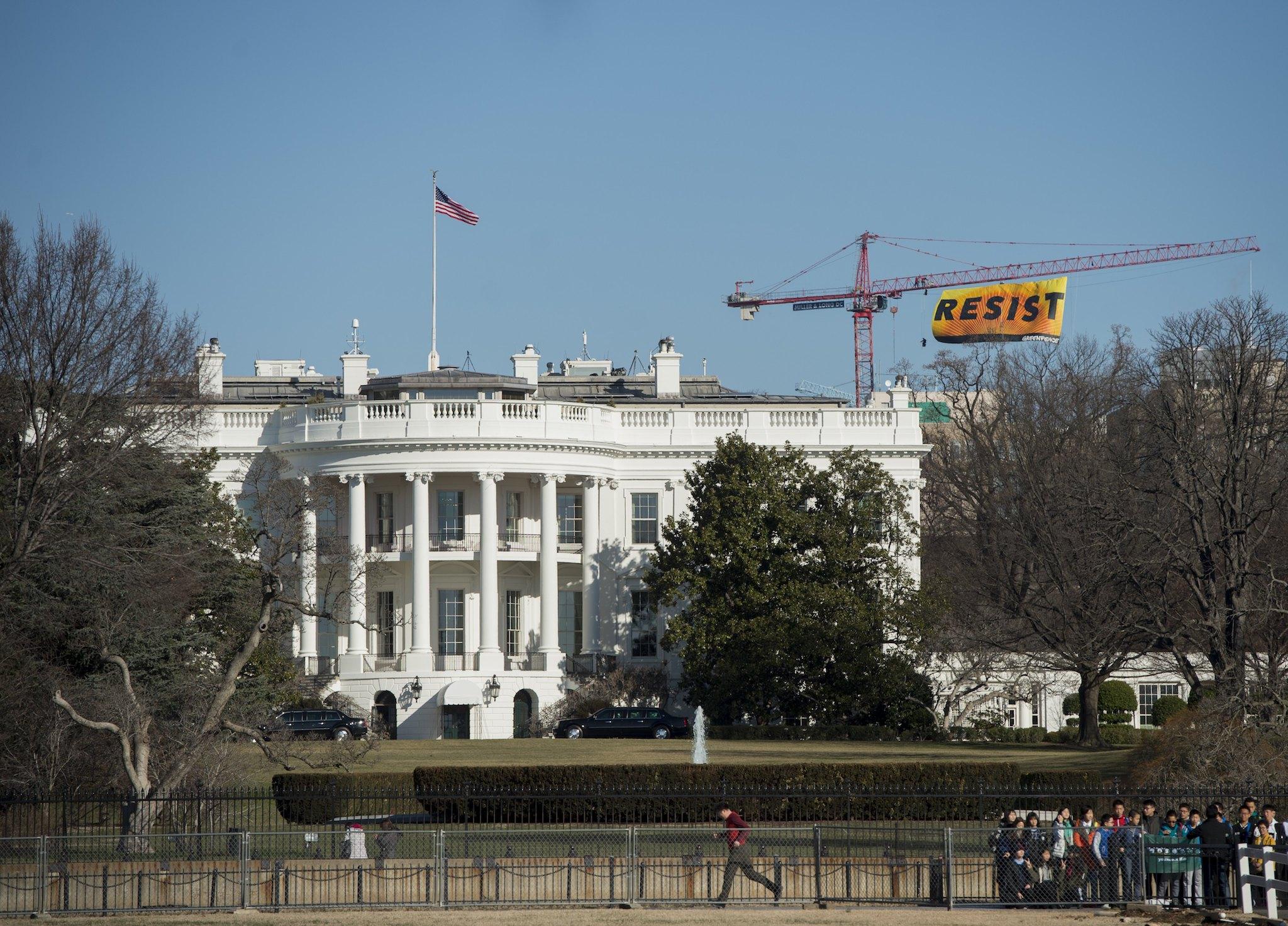 Greenpeace protesters unfold a banner reading 'Resist' from atop a construction crane behind the White House January 25, 2017 in Washington, DC