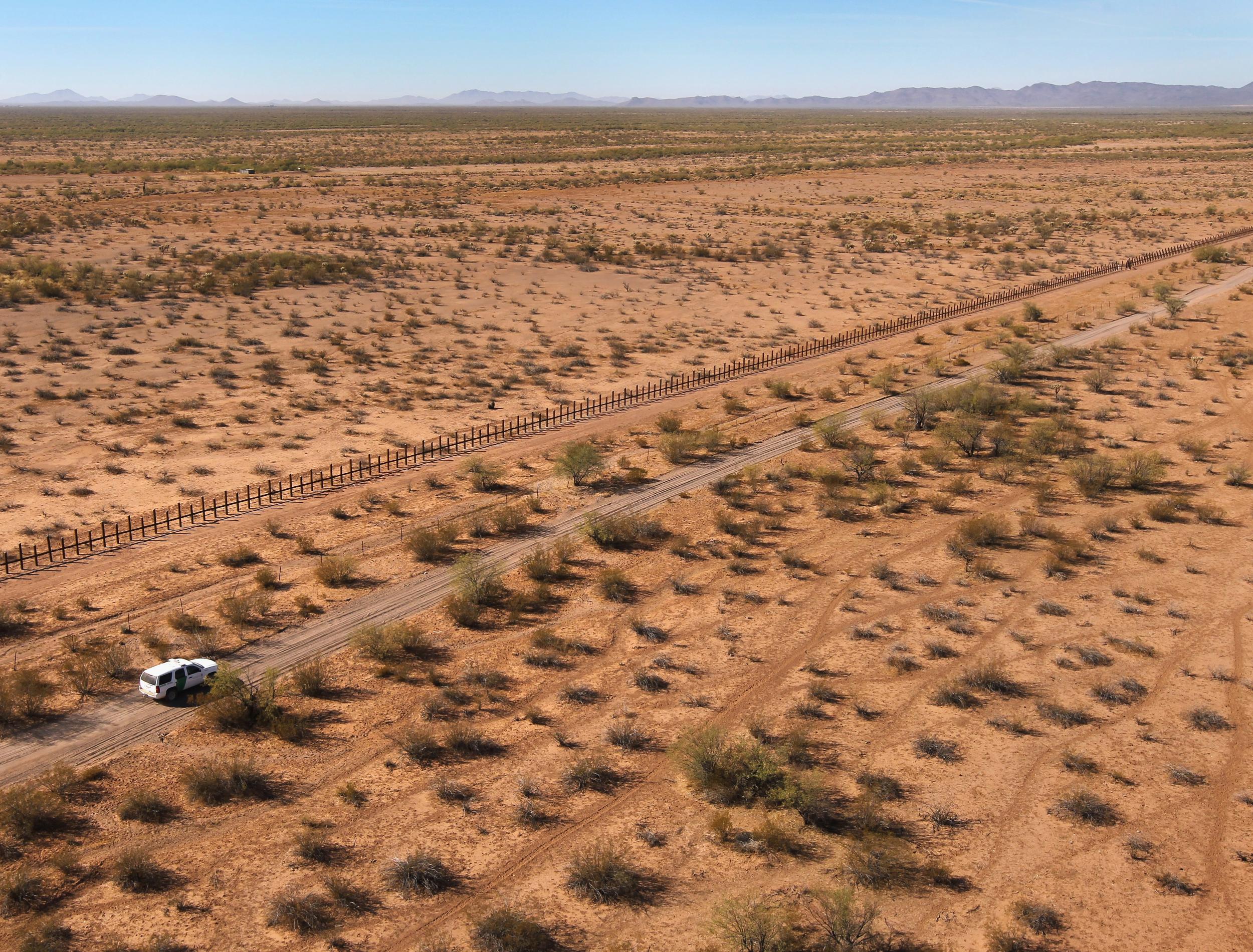 Border Patrol agents drive along the US-Mexico border fence in the Tohono O'odham Reservation, Arizona