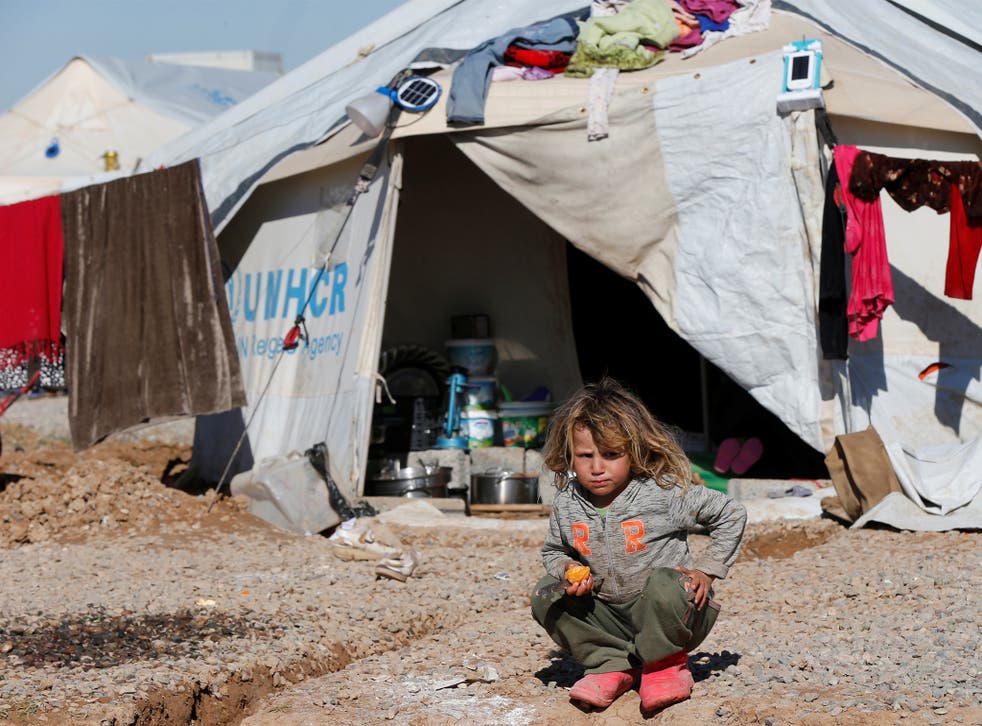 A displaced Iraqi child who fled the Isis-held city of Mosul sits in front of a tent in a camp at Hassan Sham