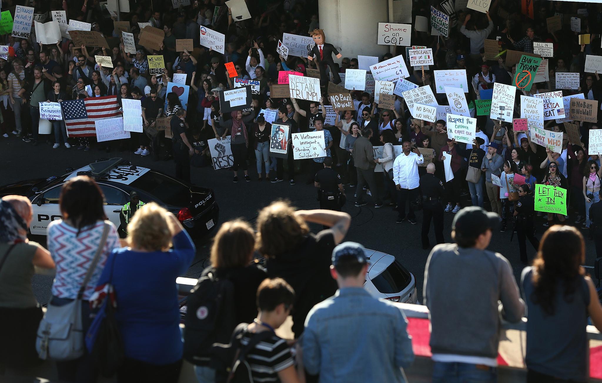 Protesters hold signs during a demonstration against the immigration ban that was imposed by U.S. President Donald Trump at Los Angeles International Airport on January 29, 2017