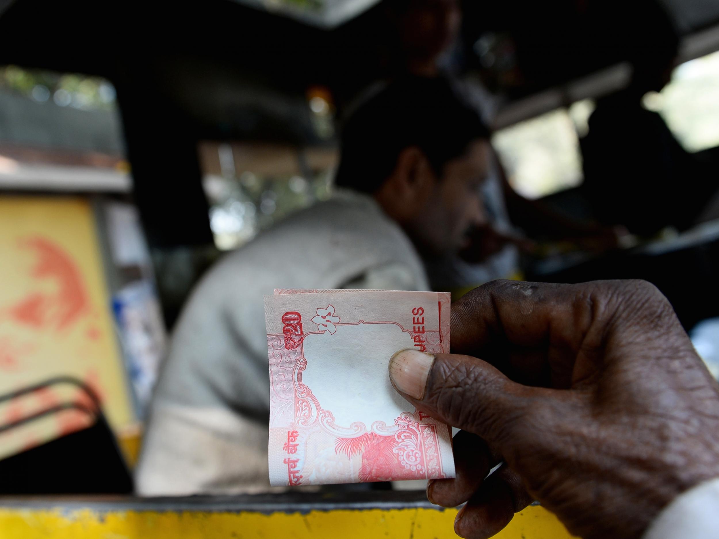 An Indian customer holds a twenty rupee note at a food stall in New Delhi
