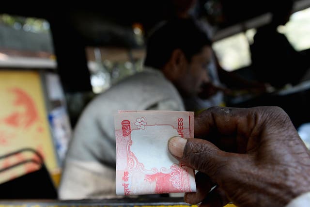 An Indian customer holds a twenty rupee note at a food stall in New Delhi