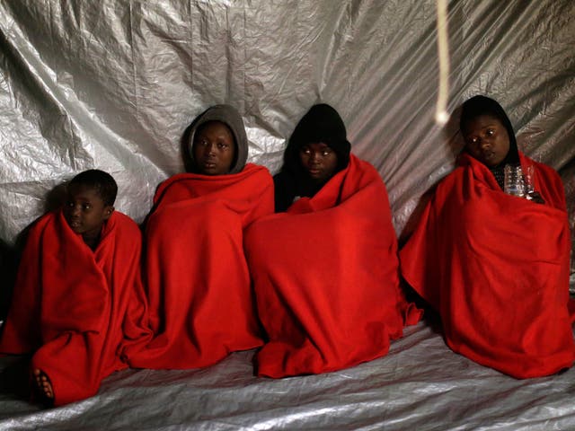Sub-Saharan refugees sit on the deck of the Golfo Azzurro after being rescued in the Mediterranean Sea on 27 January