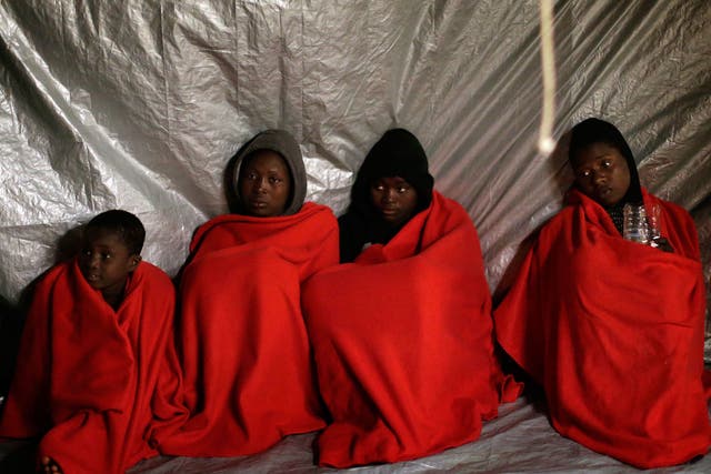Sub-Saharan refugees sit on the deck of the Golfo Azzurro after being rescued in the Mediterranean Sea on 27 January
