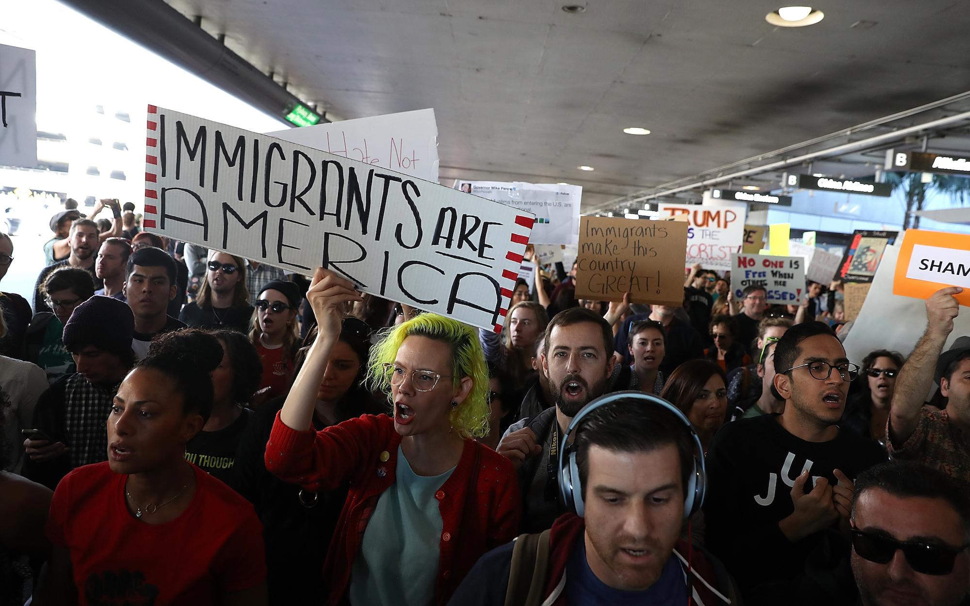 Protesters hold signs during a demonstration against the immigration ban that was imposed by U.S. President Donald Trump at Los Angeles International Airport on January 29, 2017 in Los Angeles, California.