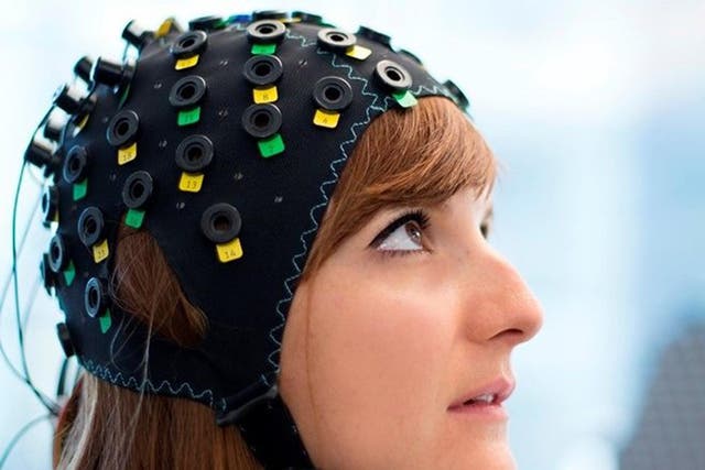 The cap uses infrared light to spot variations in blood flow in different regions of the brain (posed by a model)