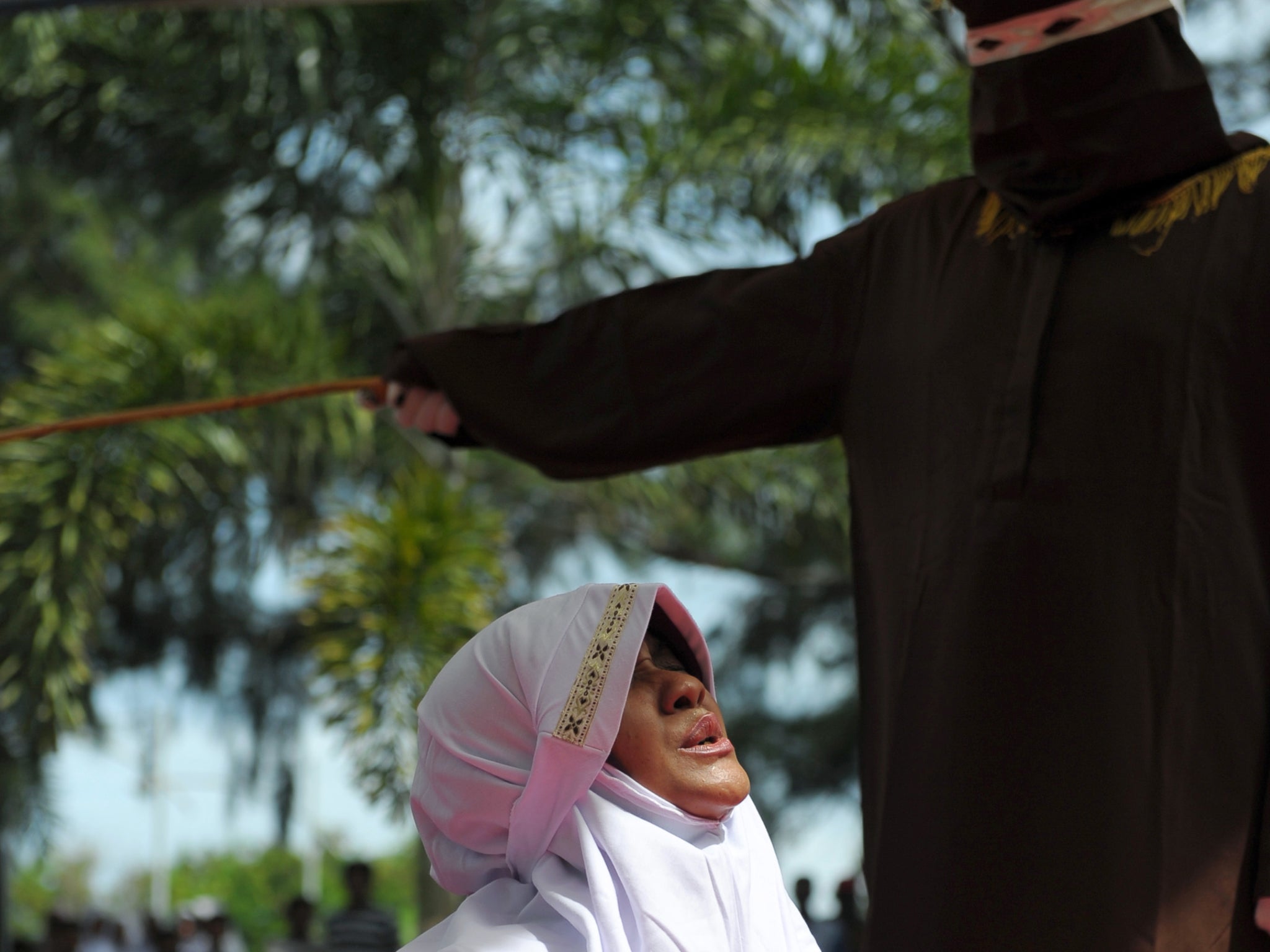 A religious officer canes an Acehnese woman for spending time in close proximity with a man who is not her husband, which is against Sharia law, in Banda Aceh