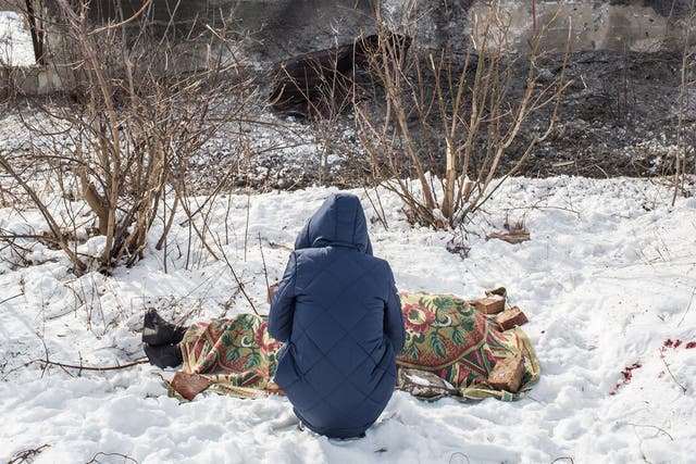 A young woman grieves over the body of her mother, who was killed by shelling in Avdiivka