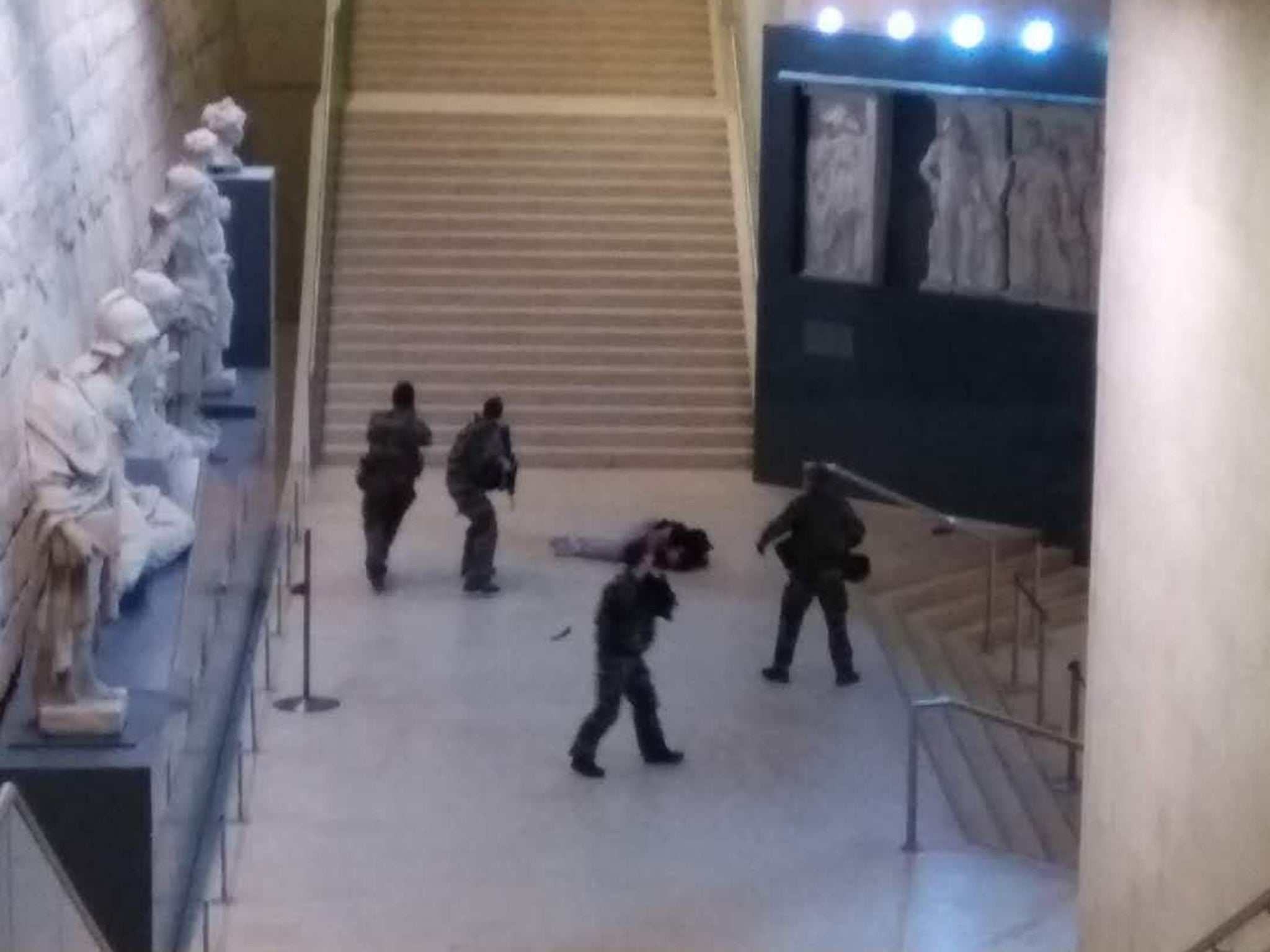 Photo taken by a tourist with a mobile phone shows a soldier opening fire at a man in the Louvre Museum