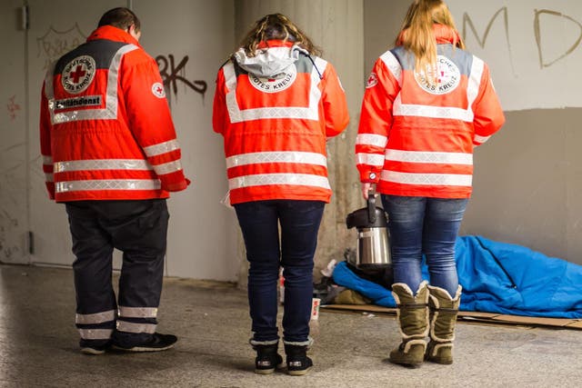 Red Cross volunteers help a homeless man