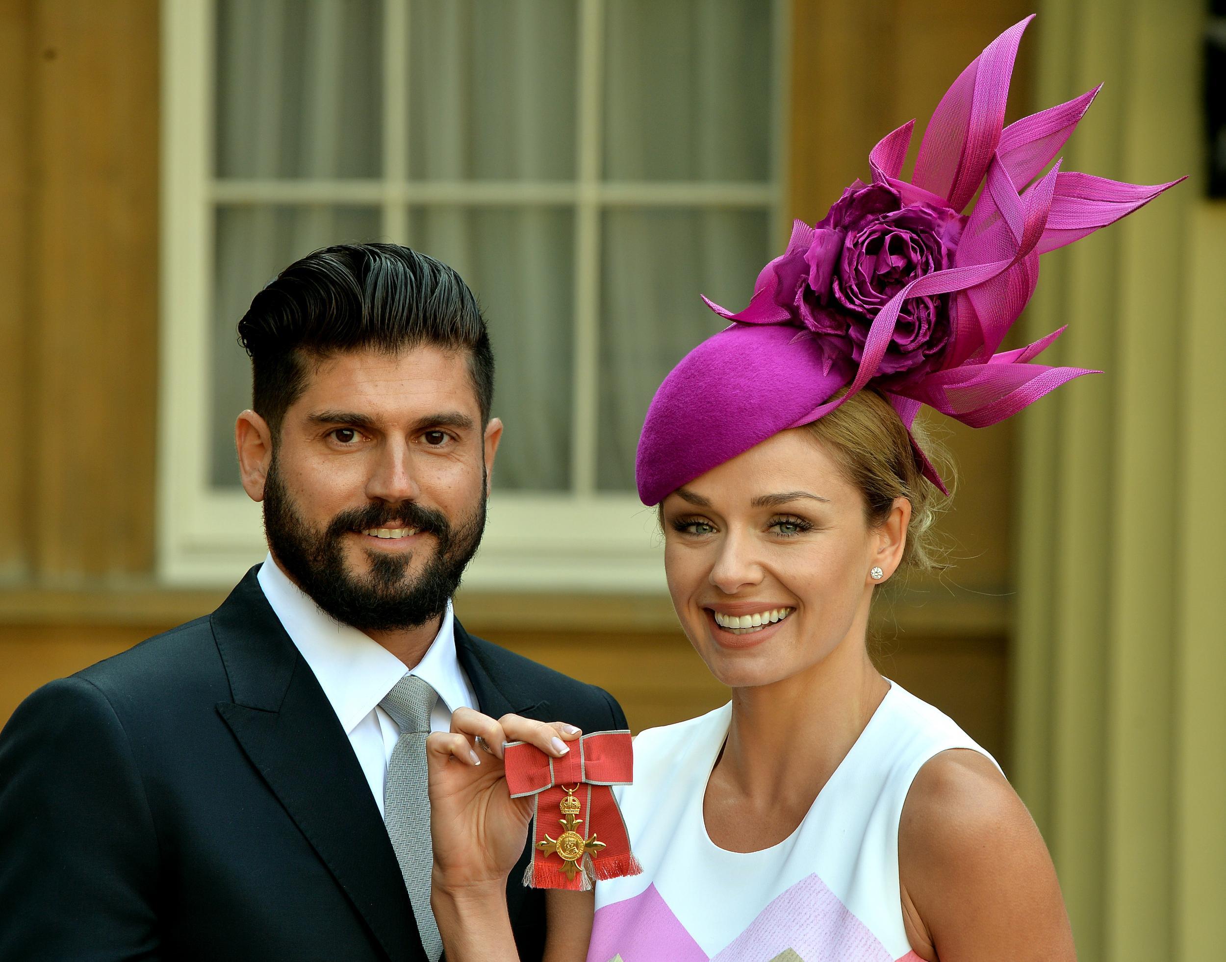 Katherine Jenkins with her partner Andrew Levitas, holding her OBE medal outside Buckingham Palace in 2014