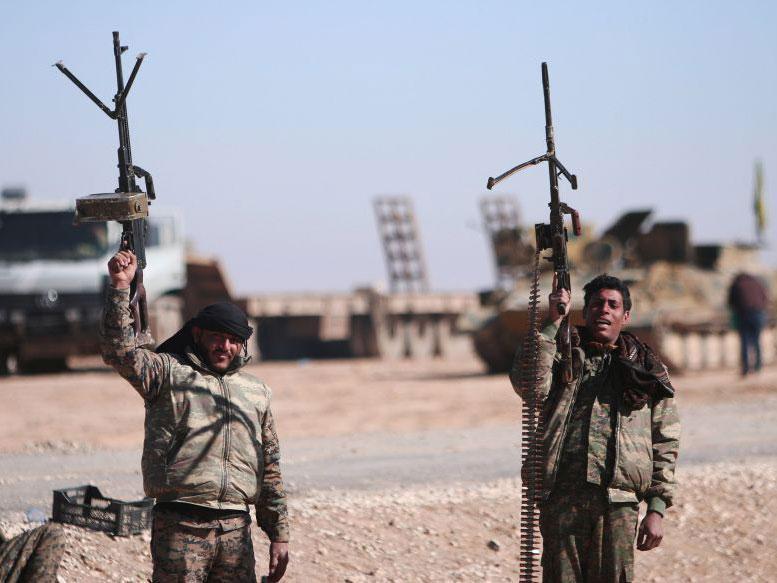 Syrian Democratic Forces fighters hold up their weapons just before the offensive on Raqqa