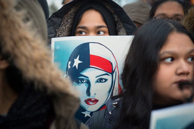 A girl holds a sign as the Astoria community stands together with Muslim-Americans and Muslim immigrants during a rally, in New York