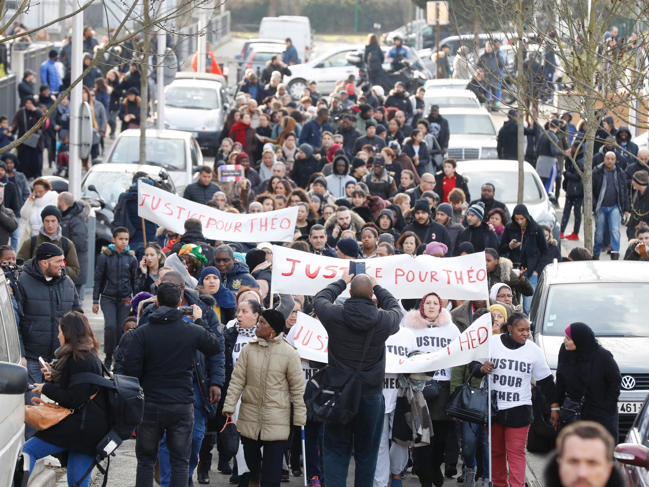 People hold a sign reading "Justice for Theo" during a protest in Aulnay-sous-Bois on Monday, a day after a French police officer was charged with the rape of a young man