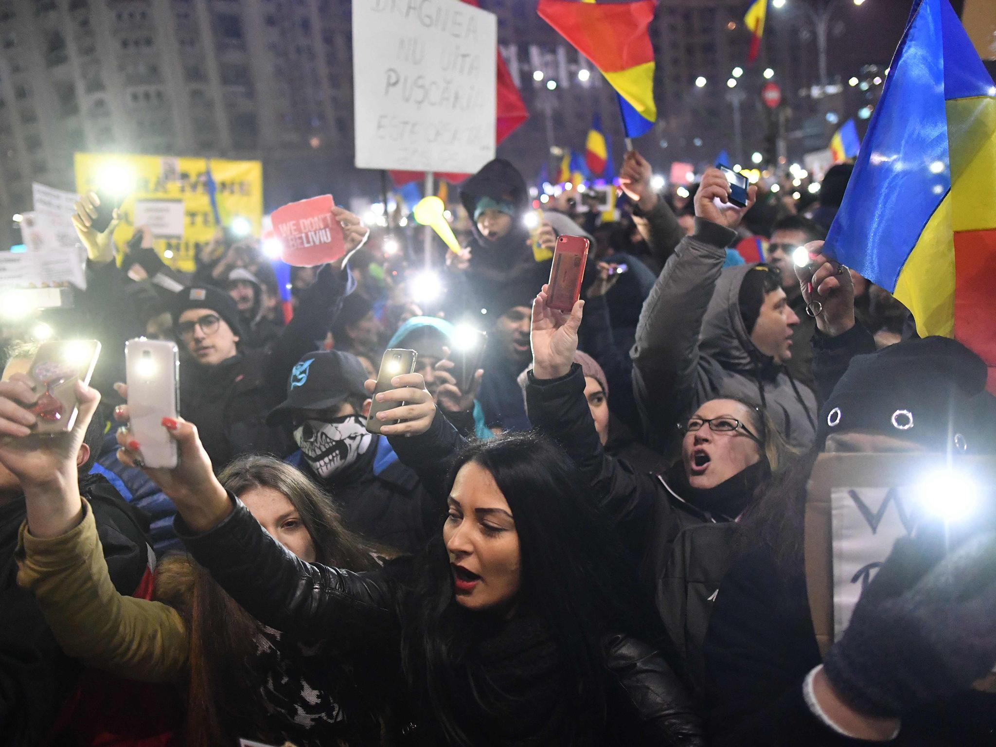Protesters turn on the lights of their mobile phones as they protest in front of the government headquarters against the government's contentious corruption decree in Bucharest, Romania