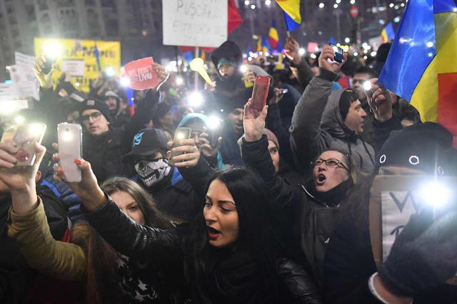 Protesters turn on the lights of their mobile phones as they protest in front of the government headquarters against the government's contentious corruption decree in Bucharest, Romania