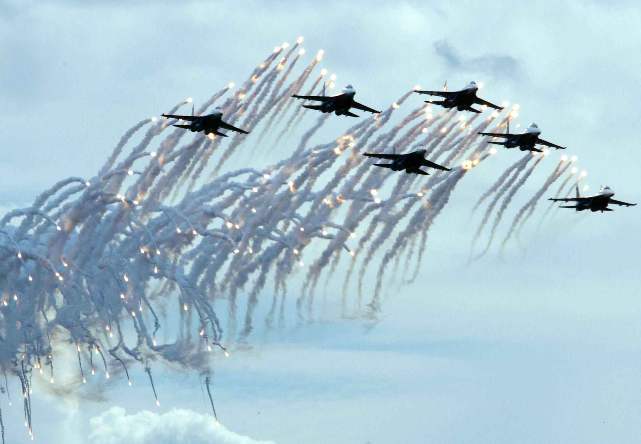 Pilots of the Russian Warriors air force aerobatic squadron fly their Su-27s and fire flares during a demonstration flight at the Moscow International Air Show