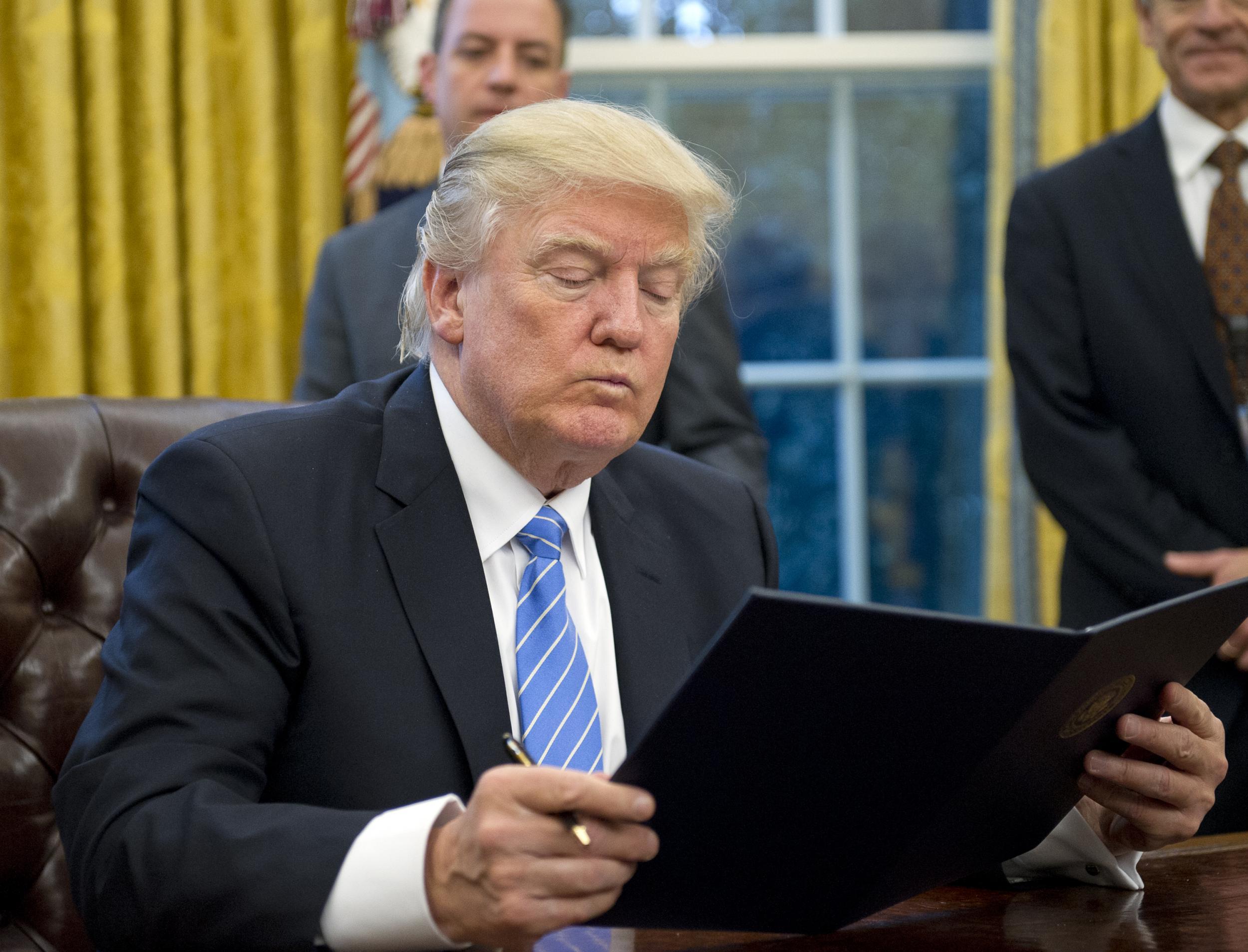 Donald Trump signing an executive order in the Oval Office