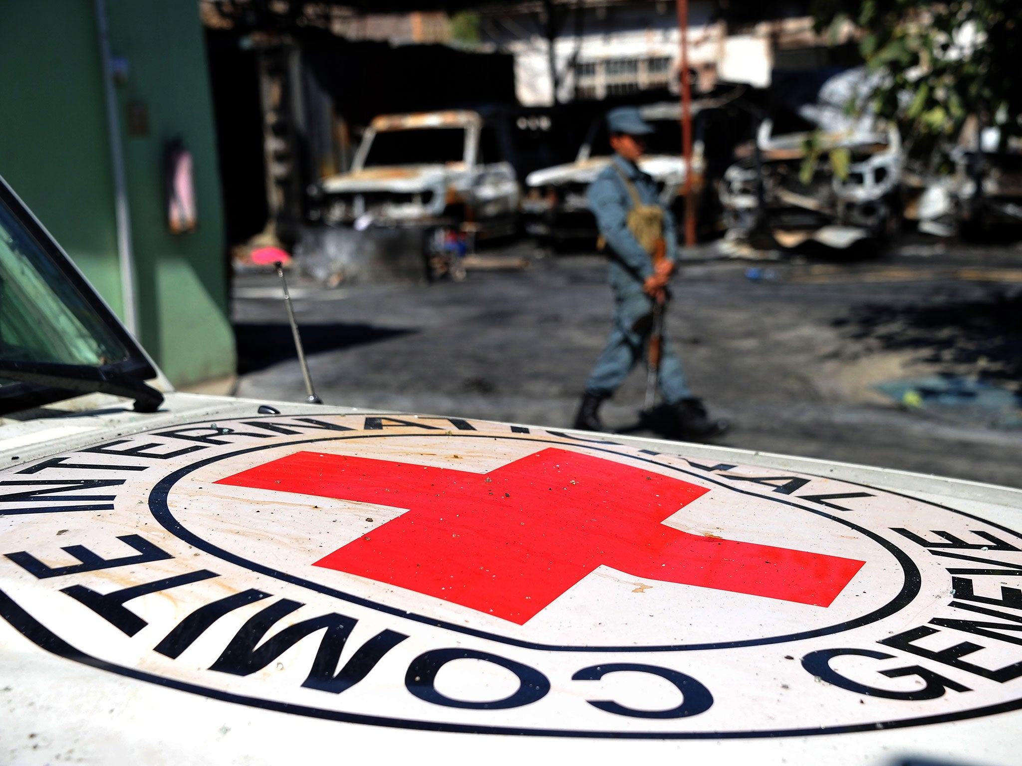 An Afghan policeman stands guard beside the burnt out wreckage of vehicles of the International Red Cross after an attack in Jalalabad on May 30, 2013