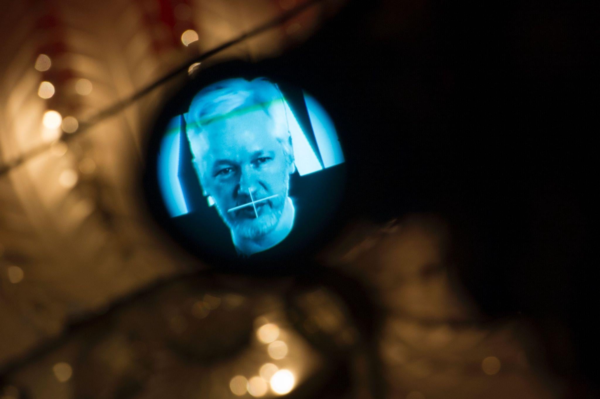 Julian Assange, founder of the online leaking platform WikiLeaks, is seen through the eyepeace of a camera as he is displayed on a screen via a live video connection during a press conference on the platform's 10th anniversary on October 4, 2016 in Berlin