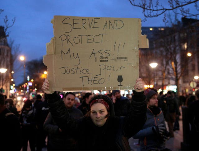 A woman holds up a placard during a protest in support of a man allegedly abused while in police custody in central Paris on February 8, 2017