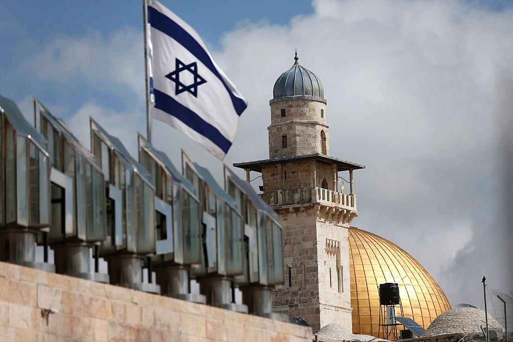 An Israeli flag flies in front of a minaret and the Dome of the Rock on the Al-Aqsa mosque compound in Jerusalem's Old City, on March 17, 2016