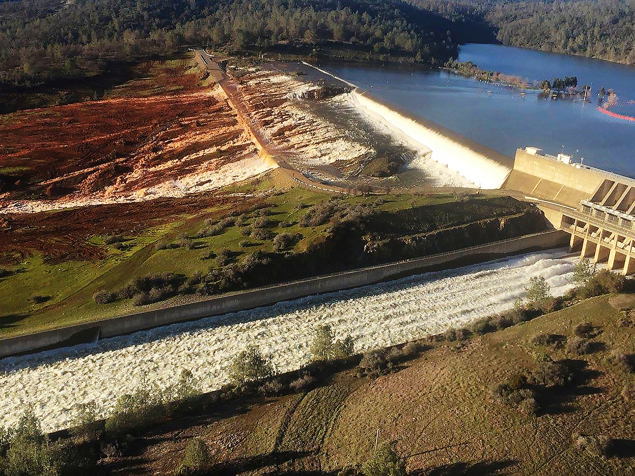 The main spillway, bottom, and an auxiliary spillway, upper, of the Oroville Dam at Lake Oroville in Oroville, Calif. Water will continue to flow over the emergency spillway at the nation's tallest dam for another day or so